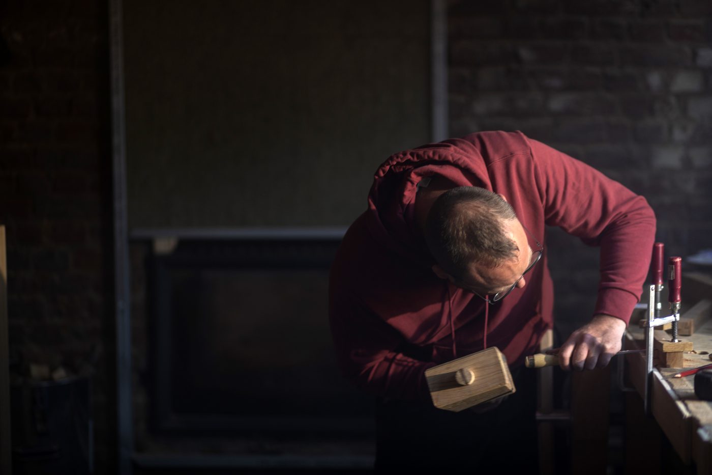 A maker bent over the bench, mallet in hand