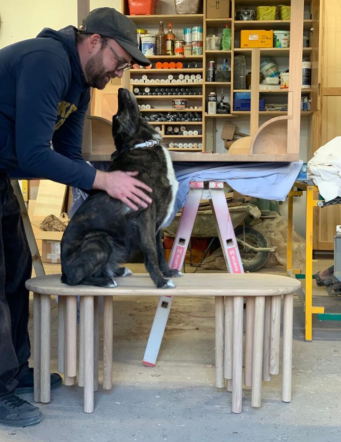 A maker and their dog on the Madame Taconeo bench, in the workshop